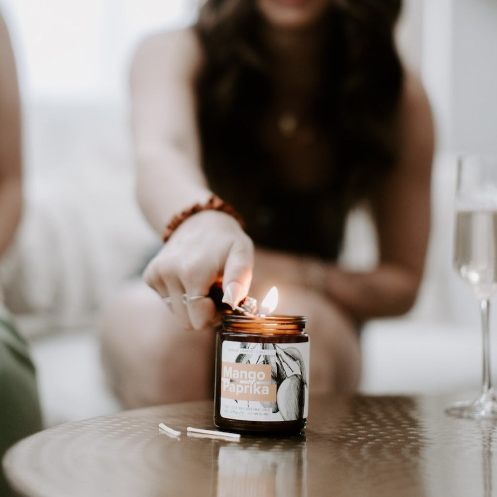 9oz Mango Paprika Soy Candle being lit by a lighter. 