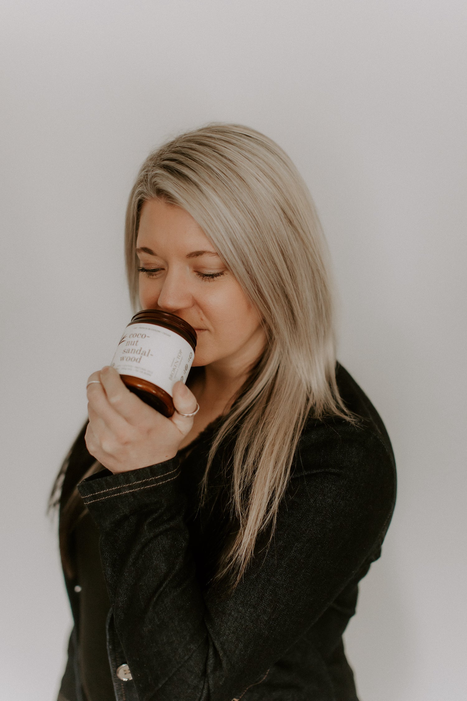 Affton Coffelt, the founder of Broken Top Brands, sniffing a 9oz Coconut Sandalwood Soy Candle.