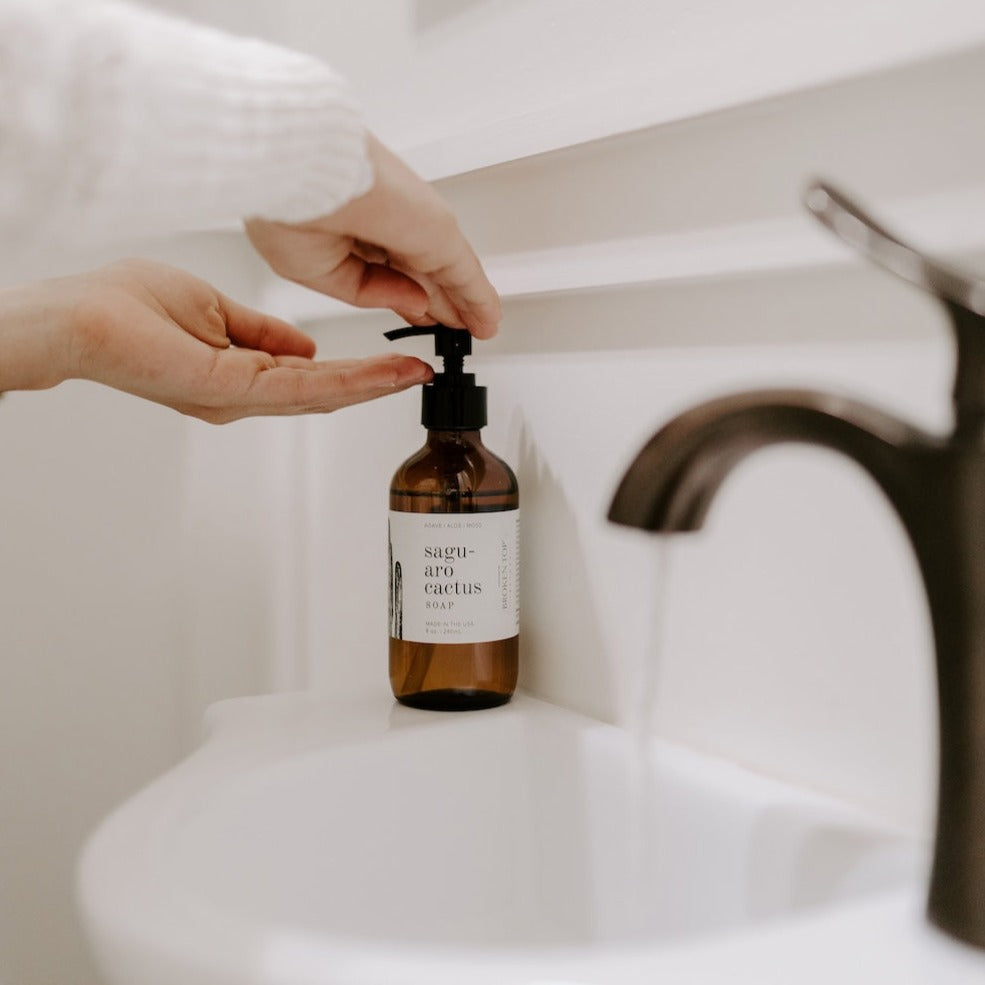 8oz Saguaro Cactus Liquid Soap being dispensed into a hand next to a sink. 