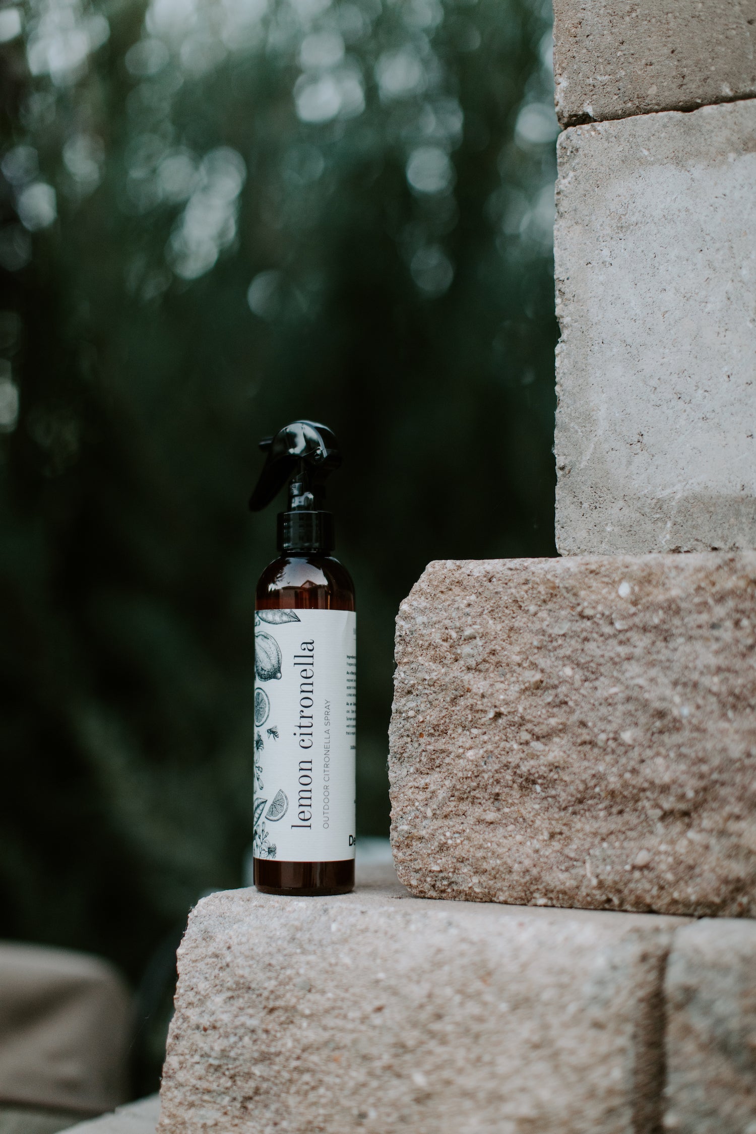 Lemon Citronella Repellent Spray perched on outdoor stone wall. 