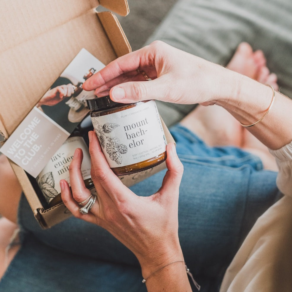 9oz Mount Bachelor Soy Candle being held by woman sitting on couch. 