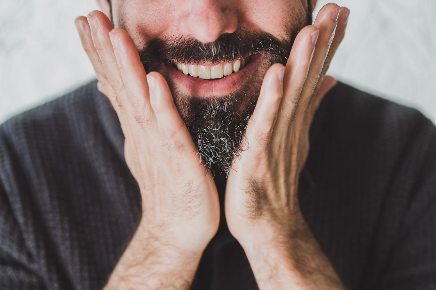 Man applying Beard Oil to his beard with two hands. 