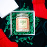 'Jolly AF' 9oz Soy Candle in a gift box next to mini red stockings.