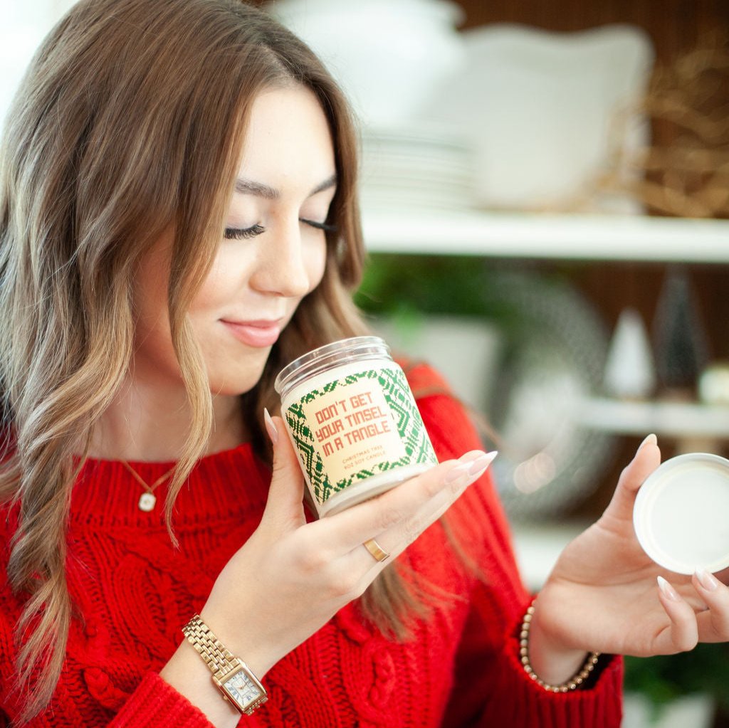 'Don't Get Your Tinsel in a Tangle' 9oz Soy Candle being smelled by a young woman. 