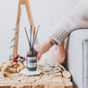 Christmas Tree Reed Diffuser on wooden table with a hand wrapped around it. 