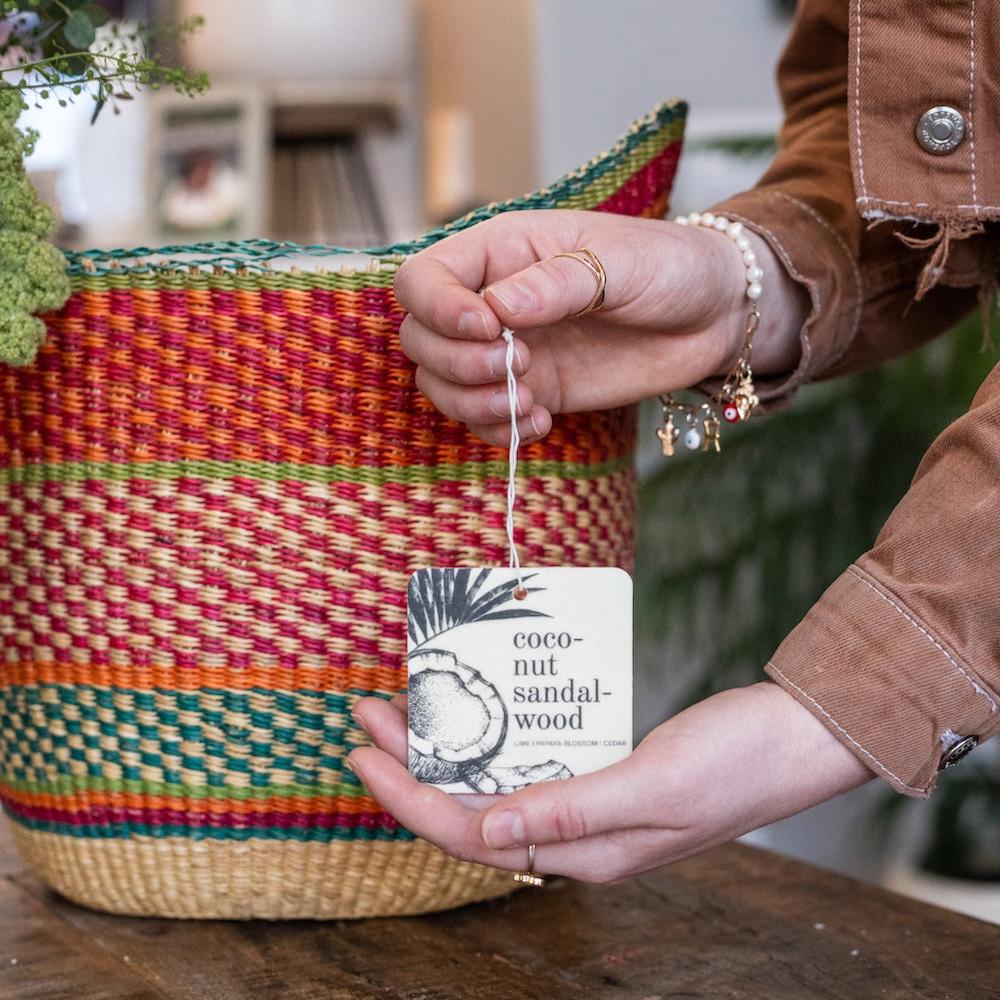 Coconut Sandalwood Car Freshener being held by two hands. 