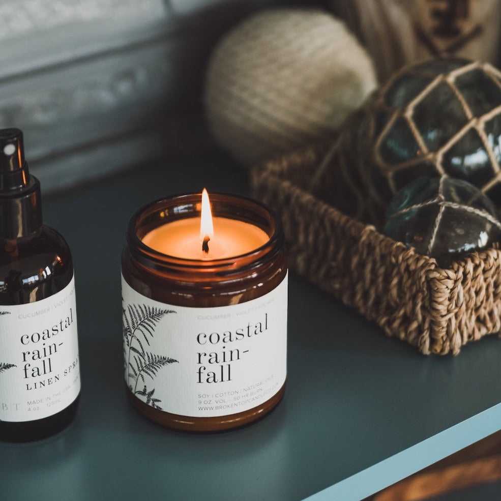 9oz Coastal Rainfall Soy Candle on shelf with Coastal Rainfall Linen Spray and house decor. 