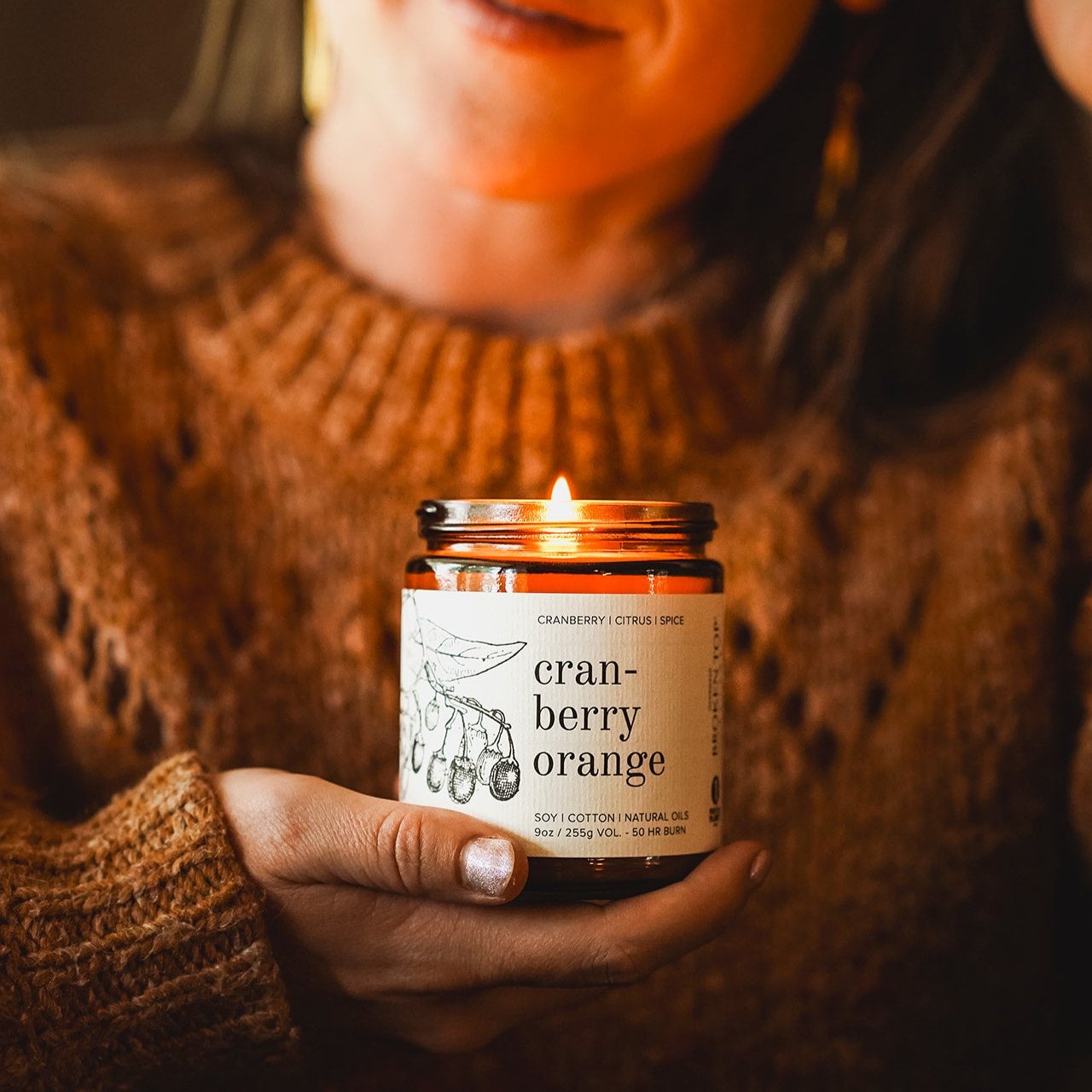 9oz Cranberry Orange Soy Candle being held by a woman. 