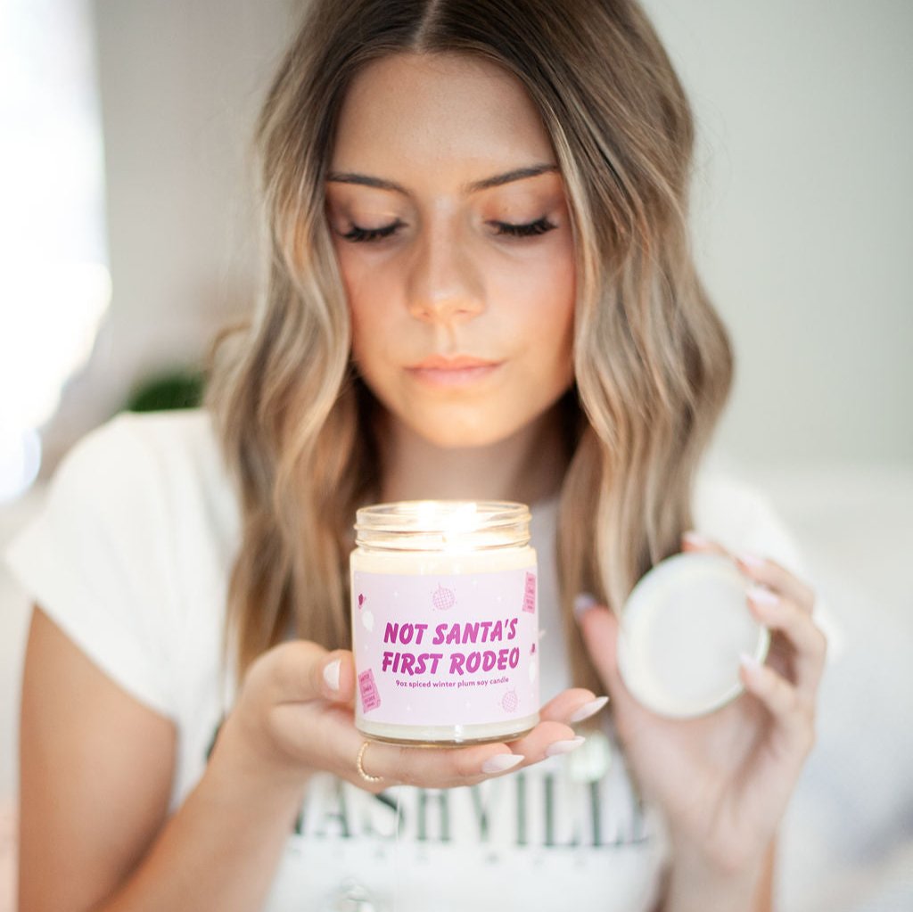 'Not Santa's First Rodeo' 9oz Soy Candle being held by a young woman. 