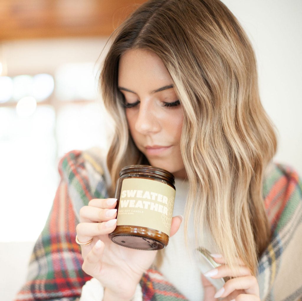 9oz 'Sweater Weather' Soy Candle being smelled by a young woman. 