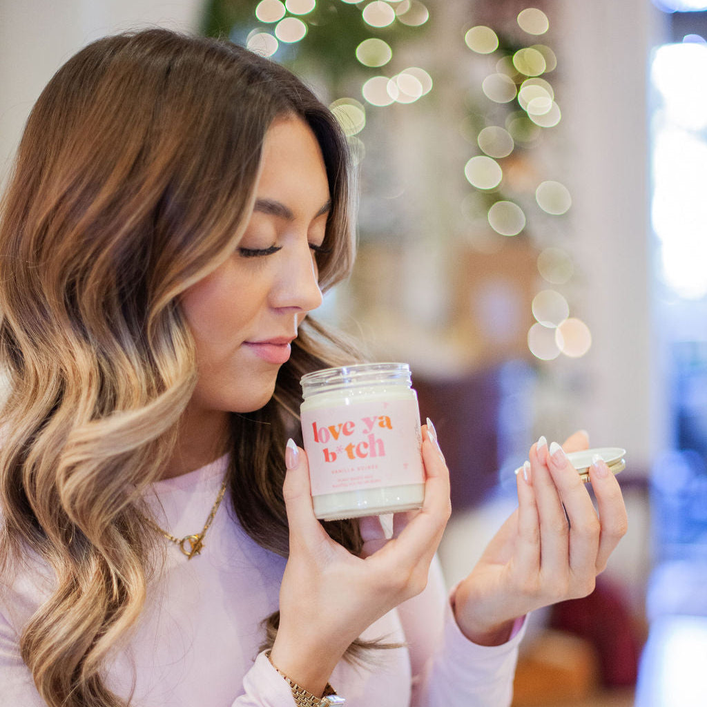 9oz 'Love Ya B*tch' Soy Candle being smelled by a young woman. 