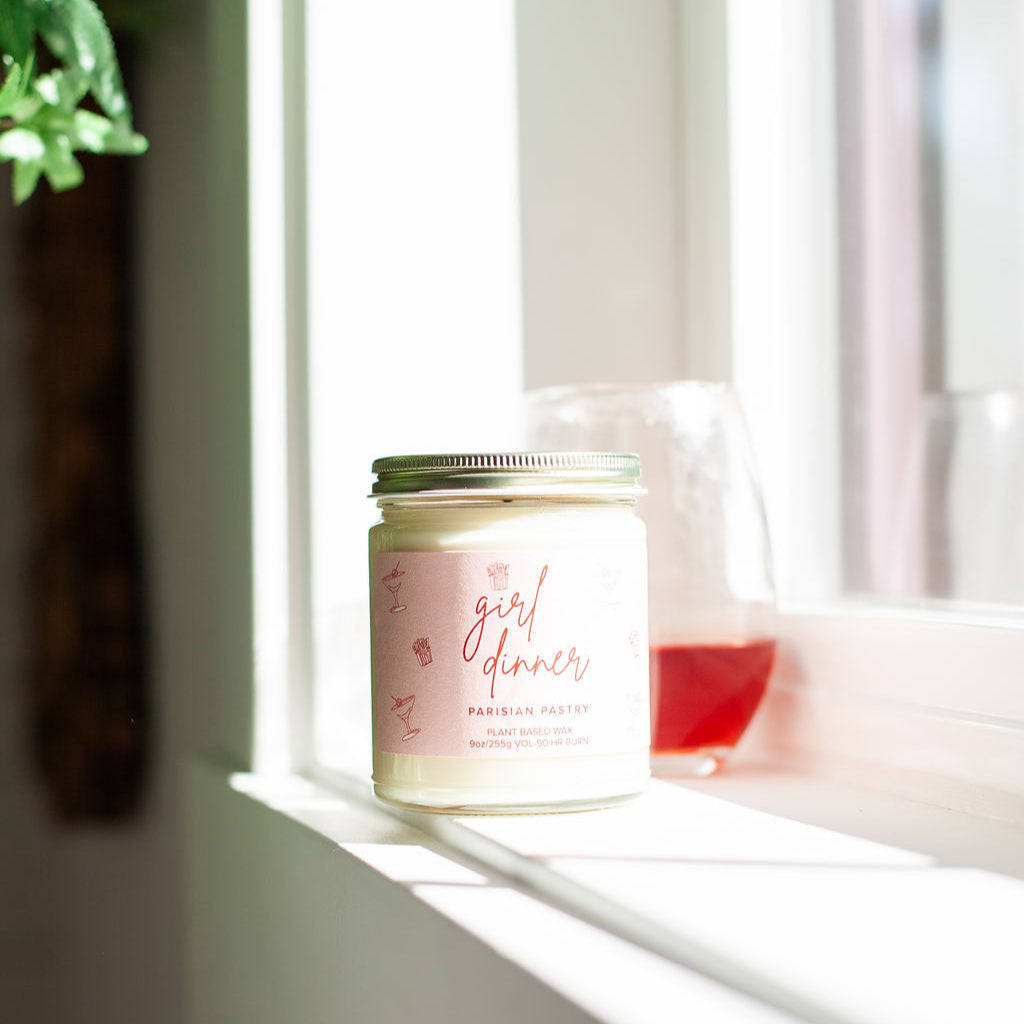 9oz 'Girl Dinner' Soy Candle on a window sill. 