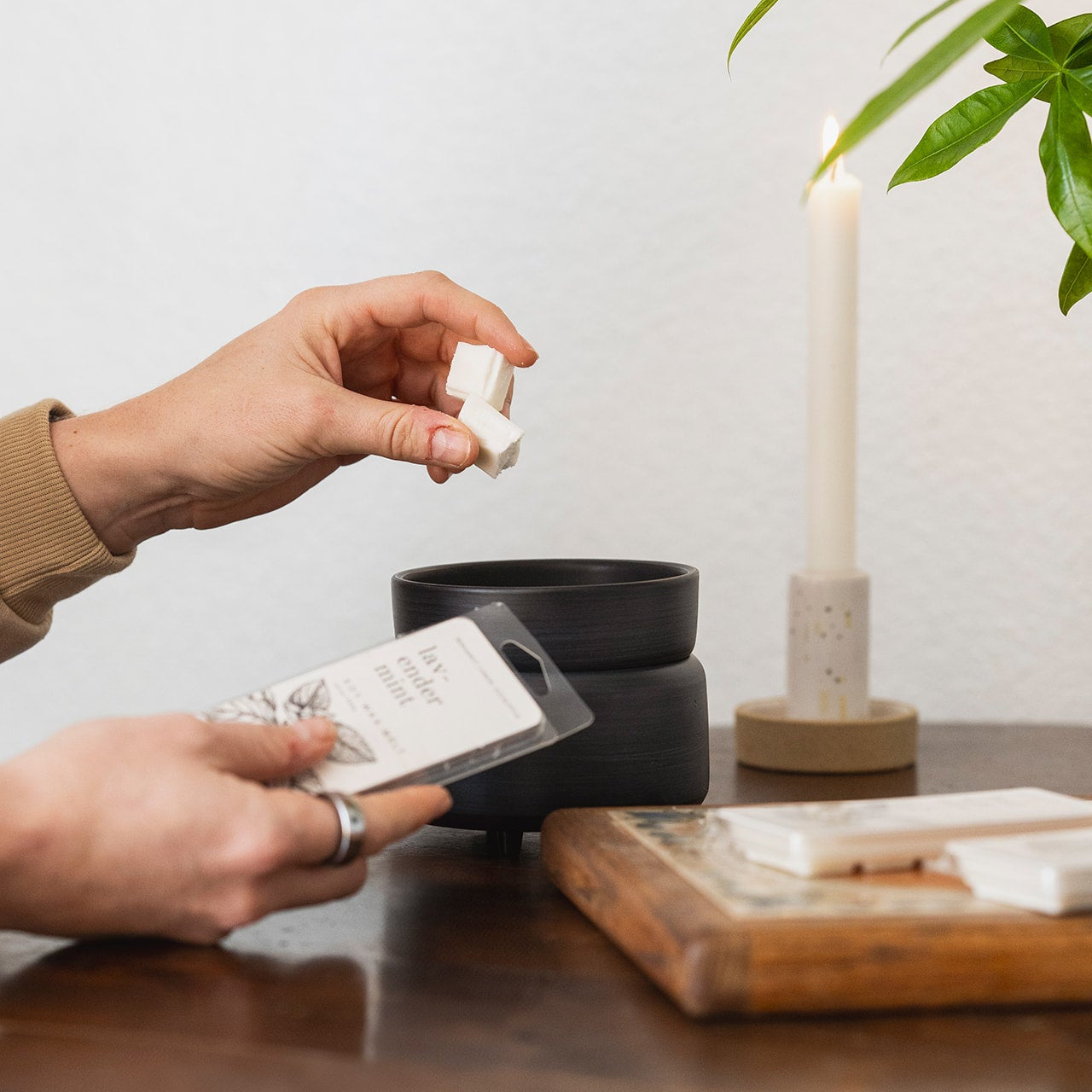 Lavender Mint Soy Wax Melt being placed into a black wax melter by hands. 