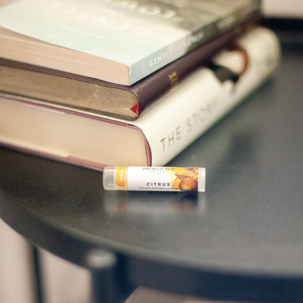 Citrus Lip Balm on a side table next to a stack of books. 