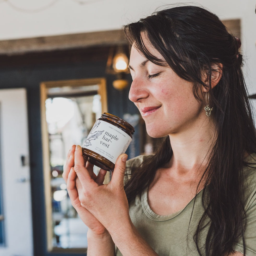 9oz Maple Harvest Soy Candle being smelled by a woman. 