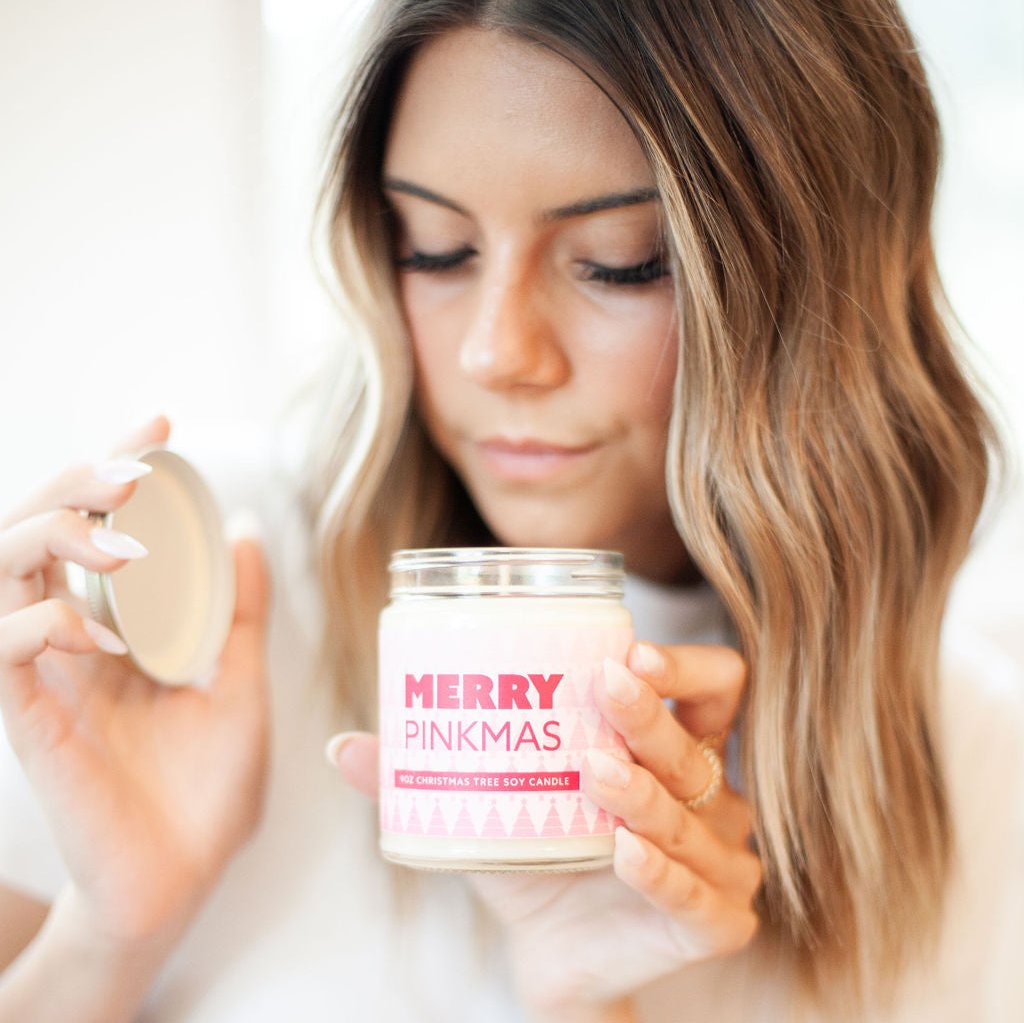 'Merry Pinkmas' 9oz Soy Candle being smelled by a young woman. 