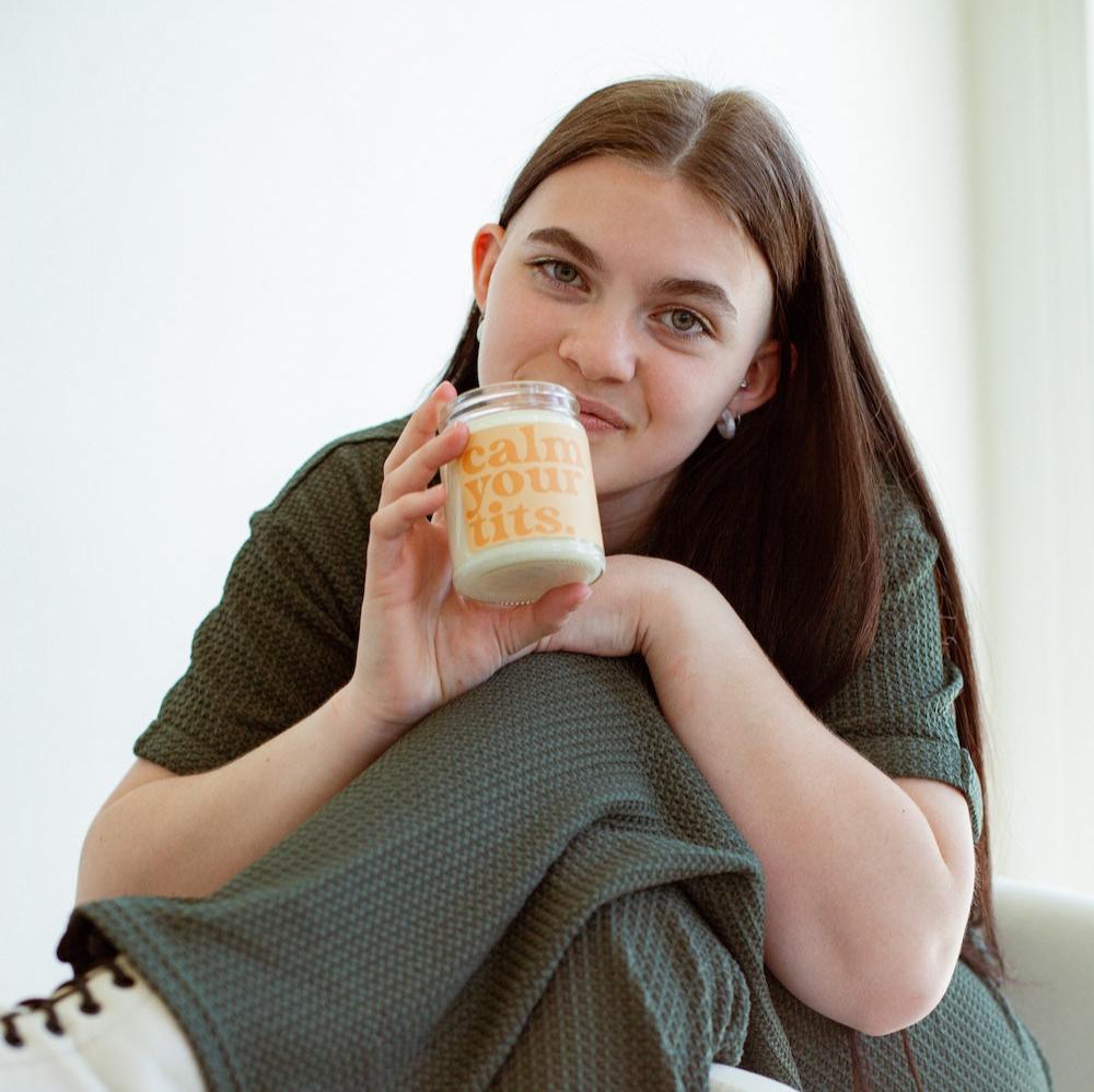 9oz 'Calm Your Tits' Soy Candle being held by a young woman. 