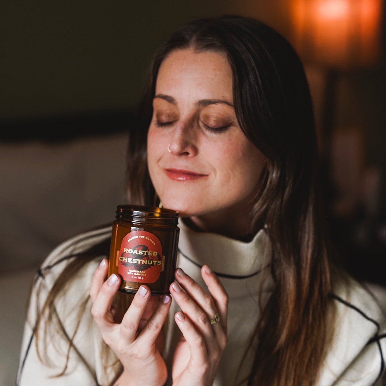 9oz Roasted Chestnuts Soy Candle being smelled by a woman.