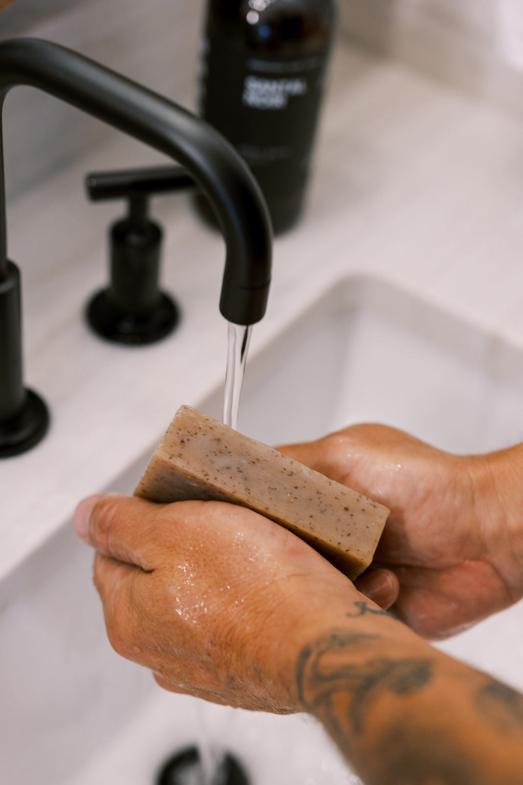 Man lathering a bar of soap in a bathroom sink. 