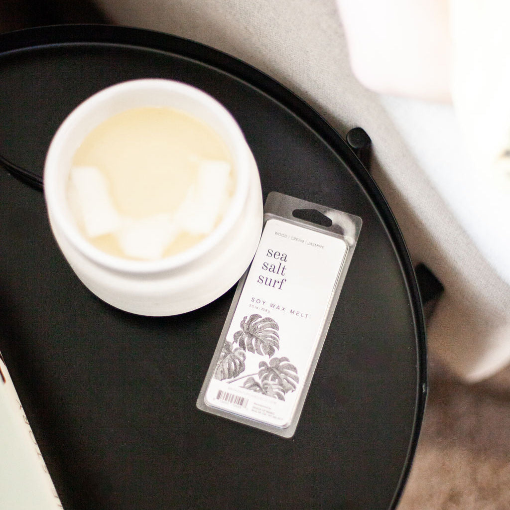 Sea Salt Surf Soy Wax Melt on black side table next to a white wax melter. 