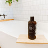 16oz Sitka Woodland Body Wash on a white bathtub. 