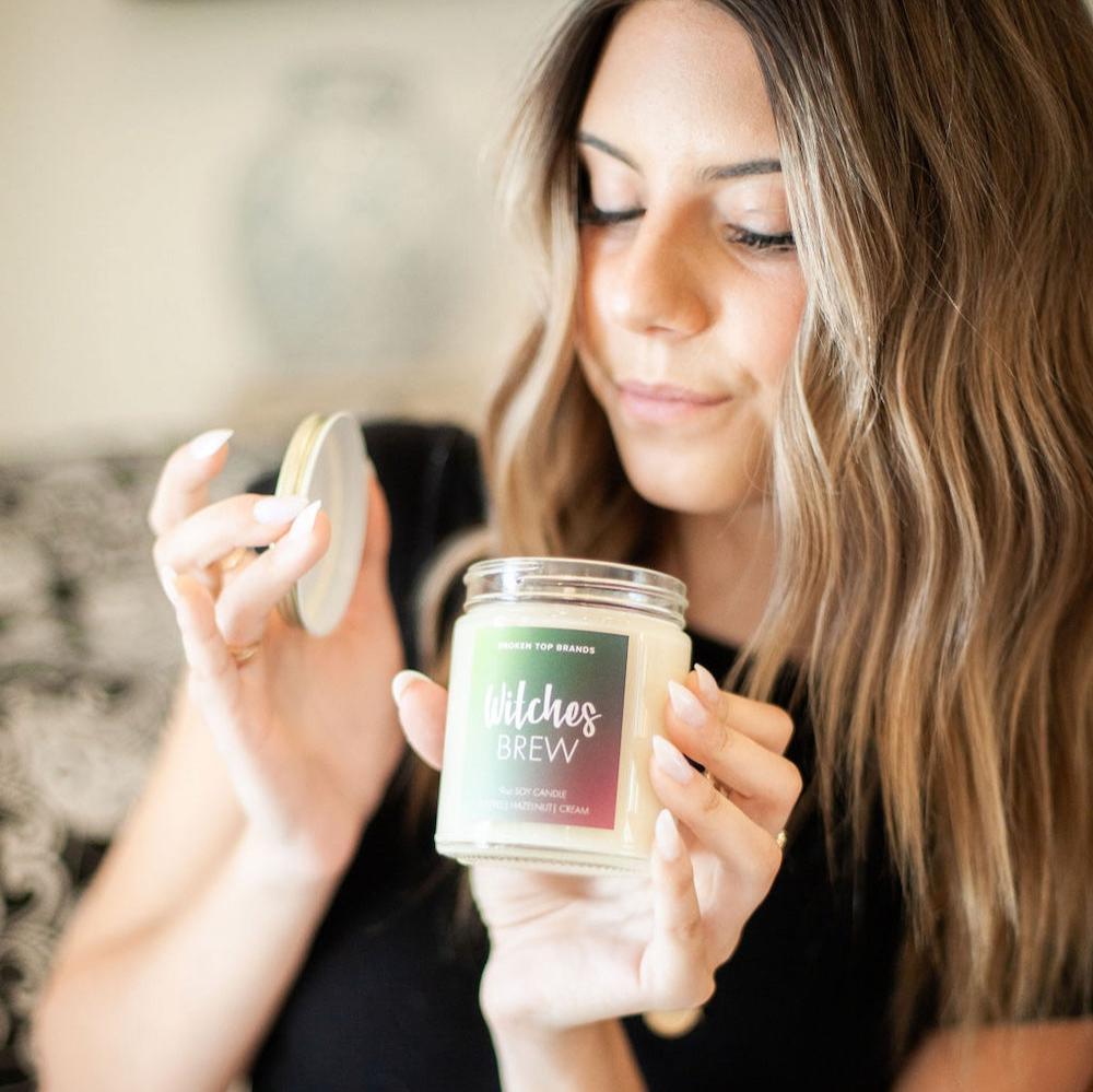 9oz 'Witches Brew' Soy Candle being smelled by a young woman. 