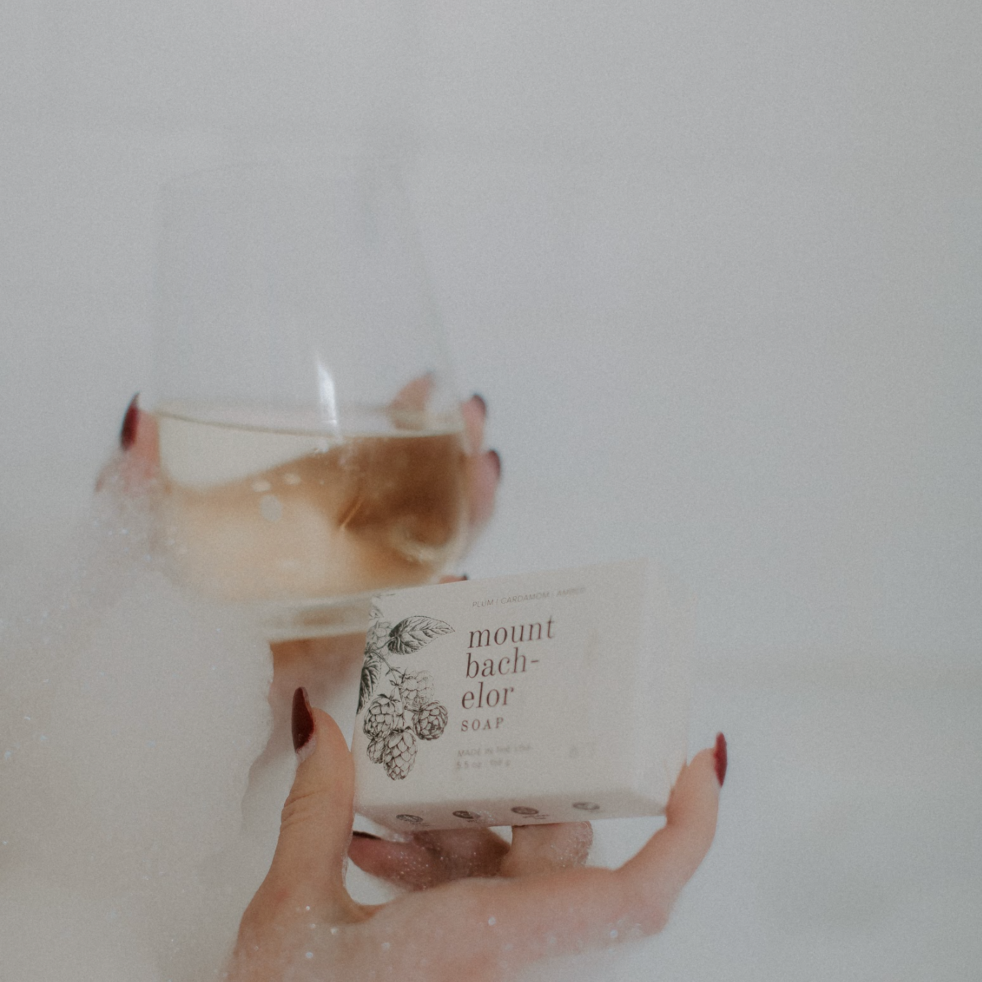 Mount Bachelor Bar Soap being held by a woman's hand next to a glass of wine. 